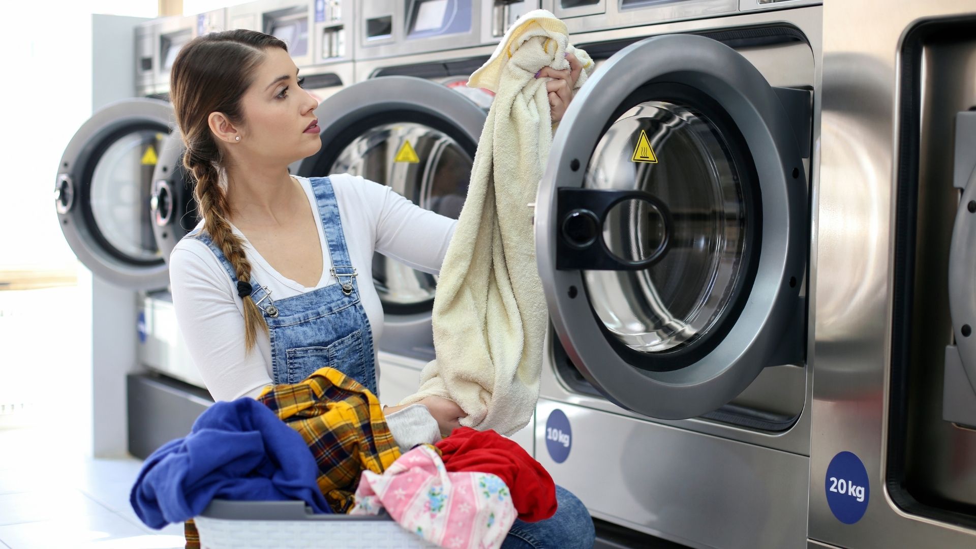 A woman is standing in front of a laundry machine.